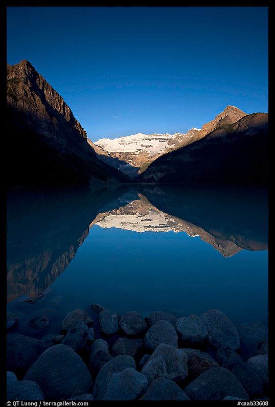 Boulders, Mirror-like Lake Louise and Victoria Peak, early morning. Banff National Park, Canadian Rockies, Alberta, Canada