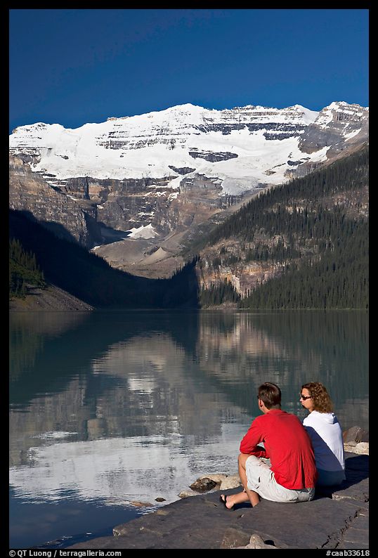 Couple sitting in the sun in front of Lake Louise, morning. Banff National Park, Canadian Rockies, Alberta, Canada