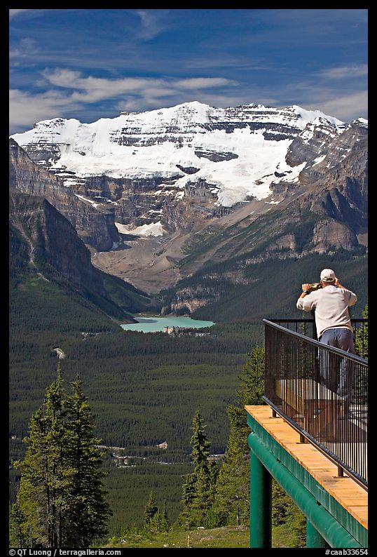 Man looking at Lake Louise through binoculars on observation platform. Banff National Park, Canadian Rockies, Alberta, Canada