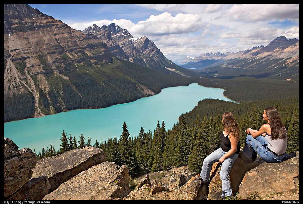 Visitors sitting on a rook overlooking Peyto Lake. Banff National Park, Canadian Rockies, Alberta, Canada