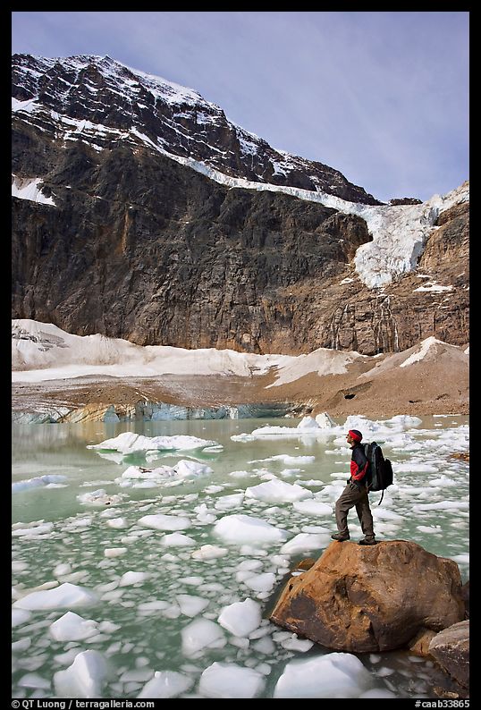 Hiker with backpack looking at iceberg-filed lake, glaciers, and mountain, Mt Edith Cavell. Jasper National Park, Canadian Rockies, Alberta, Canada
