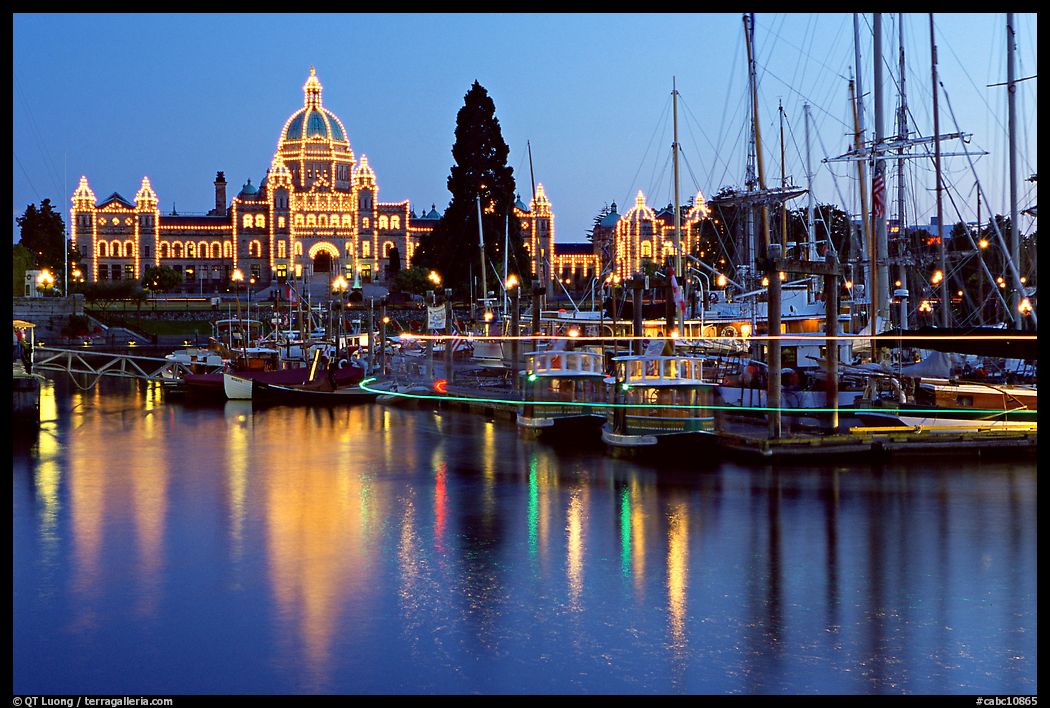 Boats in inner harbor with a trail of lights and parliament building lights. Victoria, British Columbia, Canada