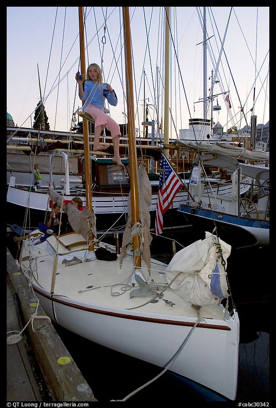 Girl swinging from the mast of a small sailboat, Inner Harbour. Victoria, British Columbia, Canada