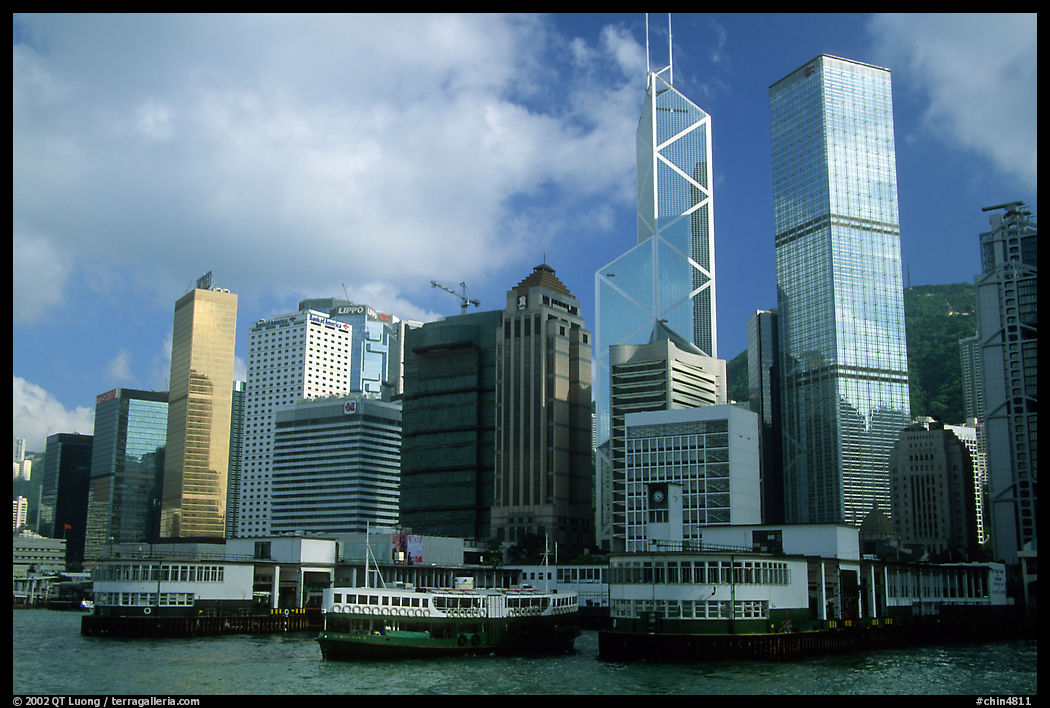A Star ferry leaves Hong-Kong island. Its symmetrical shape alleviates the need for turning around. Bank of China (369m) and Cheung Kong Center (290m) buildings in the background. Hong-Kong, China
