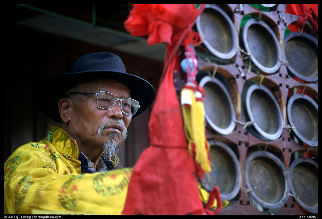 Elderly  musician playing a traditional percussion instrument. Baisha, Yunnan, China