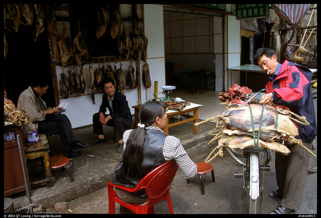 Loading roasted meat on a bicycle. Kunming, Yunnan, China