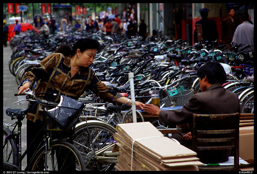 Woman checking out her bicycle at a bicycle lot. Kunming, Yunnan, China