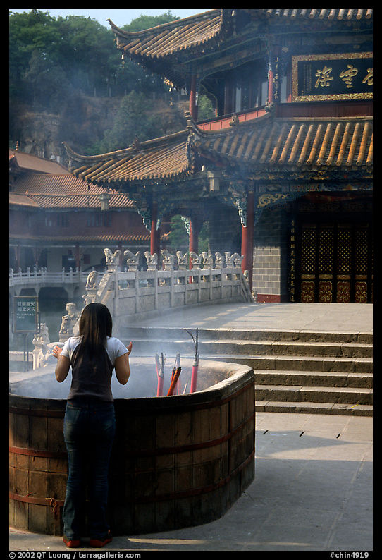 Woman offers incense in the central courtyard of Yantong Si. Kunming, Yunnan, China