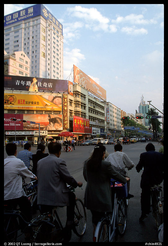 Bicyclists wait for the green light on a modern avenue. Kunming, Yunnan, China