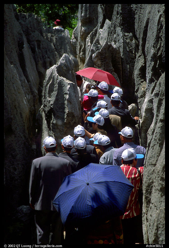 Crowds of Chinese tourists in a walkway among the limestone pillars. Shilin, Yunnan, China