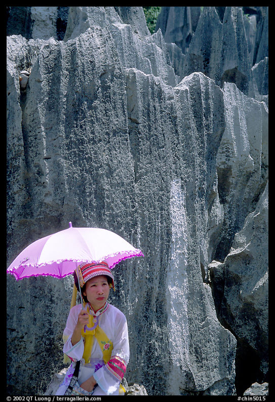 Woman from the Sani branch of the Yi tribespeople with a sun unbrella at the Stone Forest. Shilin, Yunnan, China