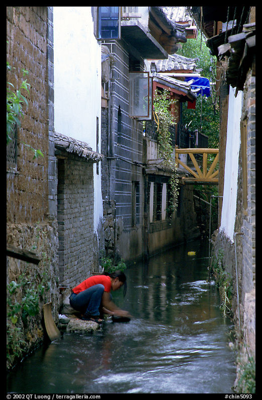 Woman washes clothes in the canal. Lijiang, Yunnan, China