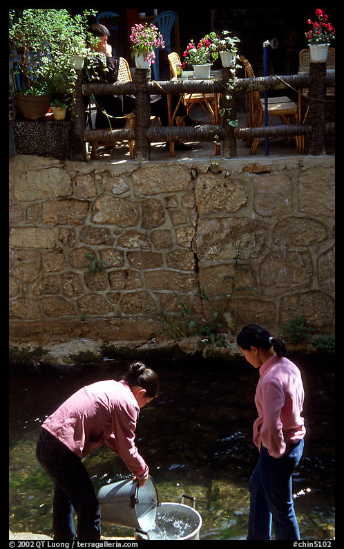 Women washing clothes in a canal. Lijiang, Yunnan, China