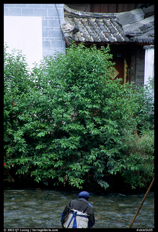 Naxi woman sitting next to a canal. Lijiang, Yunnan, China