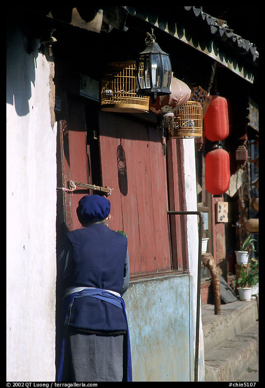 Naxi woman at the door of her wooden house. Lijiang, Yunnan, China