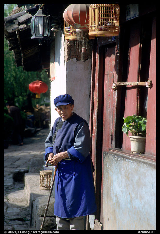 Naxi woman at the door of her wooden house. Lijiang, Yunnan, China