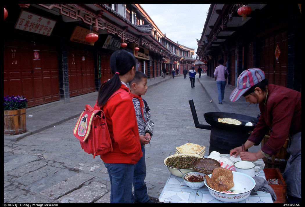 Schoolchildren get Naxi flatbread for breakfast. Lijiang, Yunnan, China