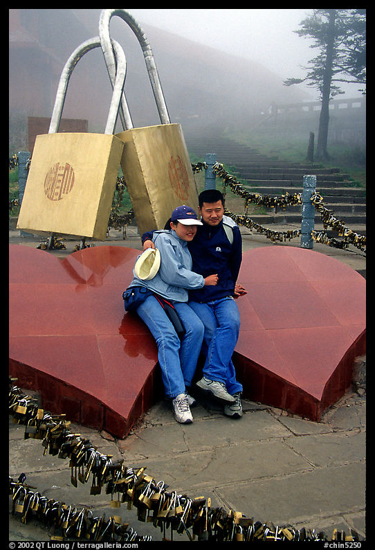 Lovers sit on top of two hearts surrounded by chain locks. Emei Shan, Sichuan, China