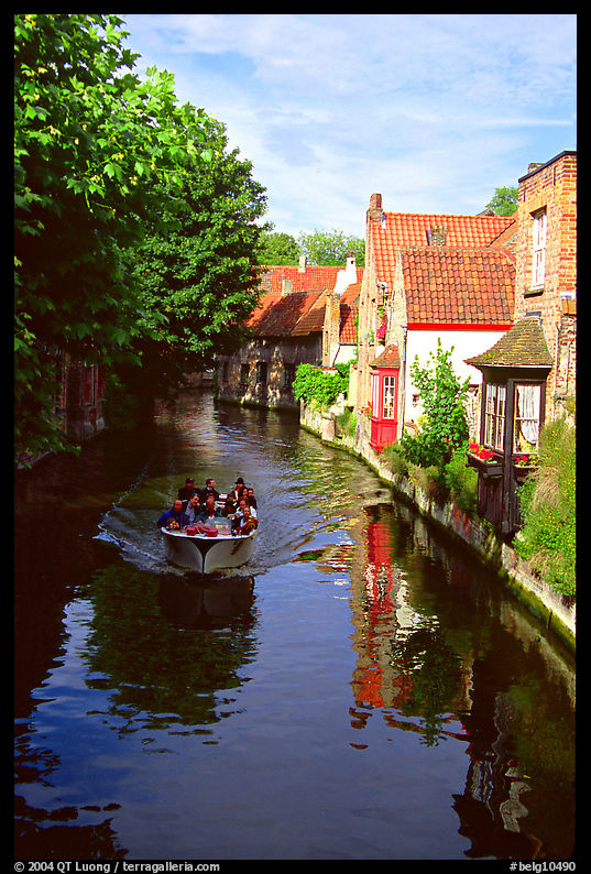 Boat on a canal lined with houses and trees. Bruges, Belgium