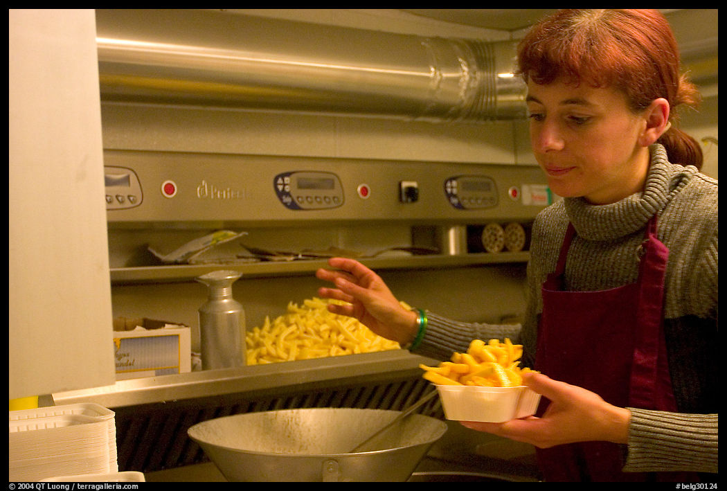 Woman preparing fries in a booth. Bruges, Belgium