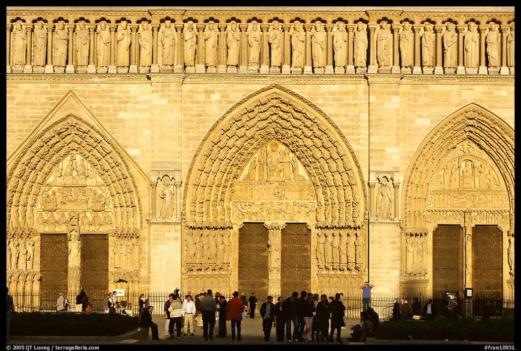 People and facade and gates of Notre Dame Cathedral, late afternoon. Paris, France