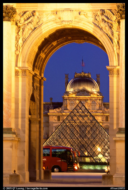Louvre, pyramid, and bus seen through the Carousel Arch at night. Paris, France