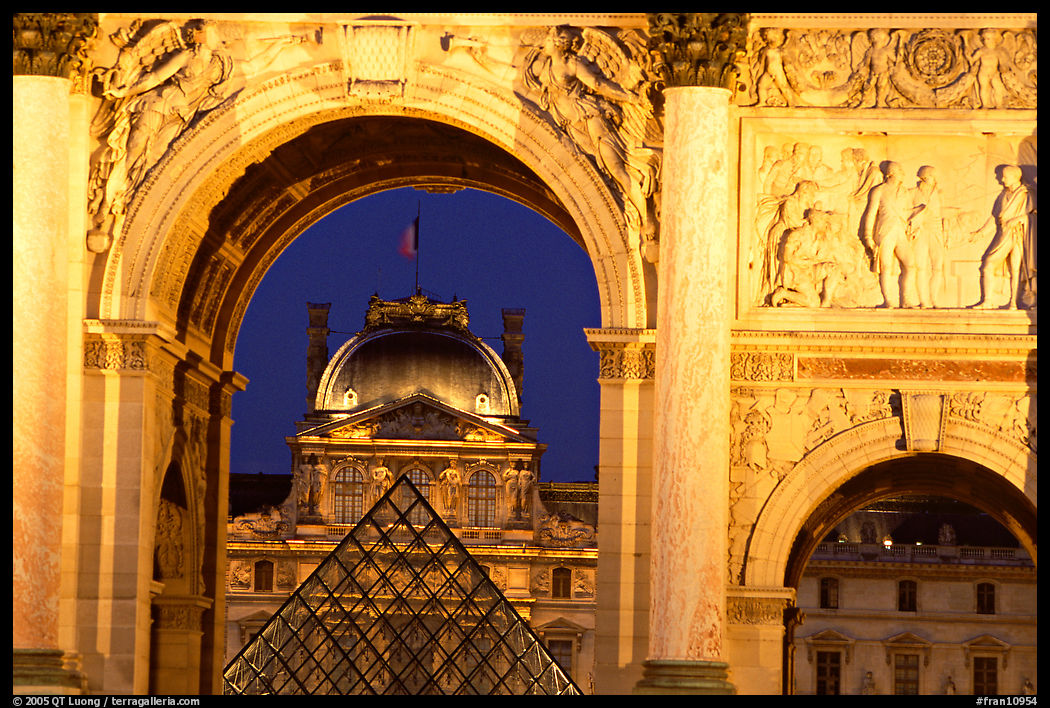 Louvre and  pyramid  seen through the Carousel triumphal arch at night. Paris, France