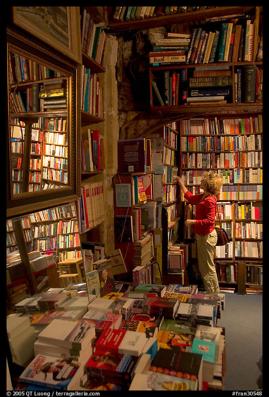 Picking-up a book in Shakespeare and Co bookstore. Paris, France