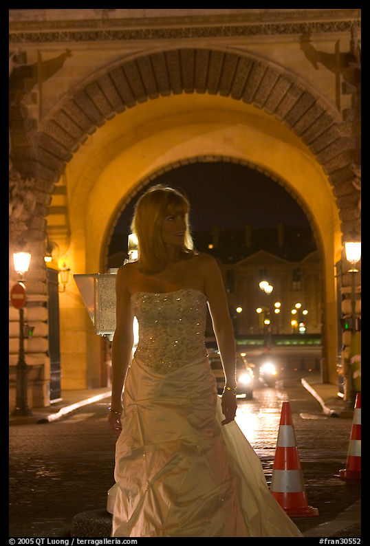Woman in bridal gown in front of the Louvre by night. Paris, France