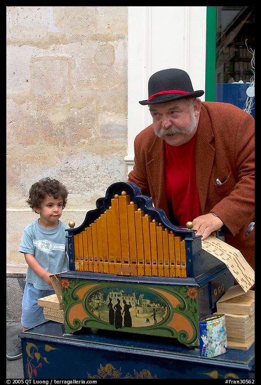Barrel organ player and kid. Paris, France