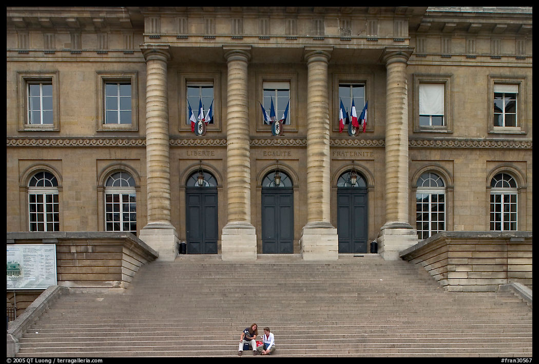 Two visitors sitting on the stairs of the Palais de Justice. Paris, France