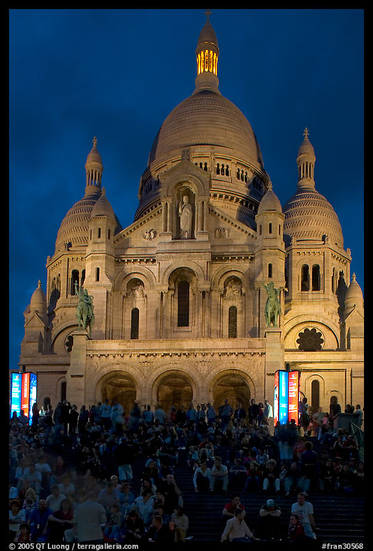 Visitors sitting on the stairs of the Sacre coeur basilic in Montmartre at night. Paris, France