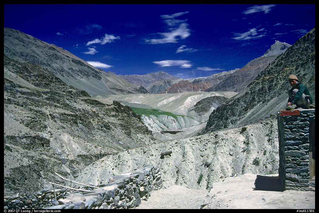 Woman sitting on roof of house in front of mountain landscape, Zanskar, Jammu and Kashmir. India