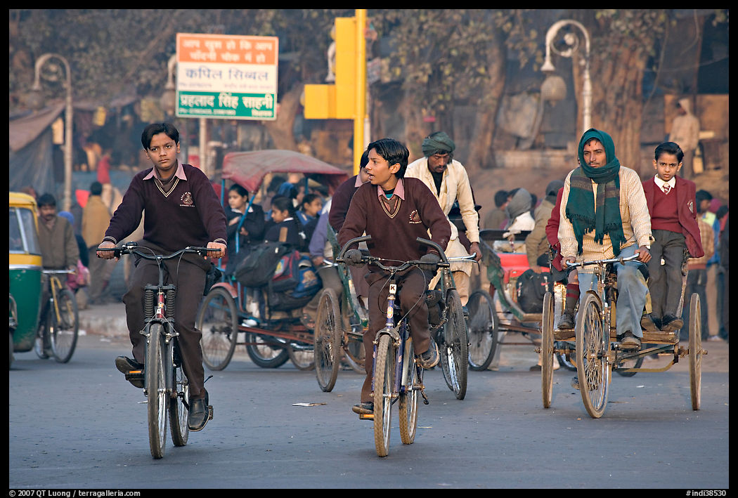Children riding bikes in rickshaws on way to school. New Delhi, India