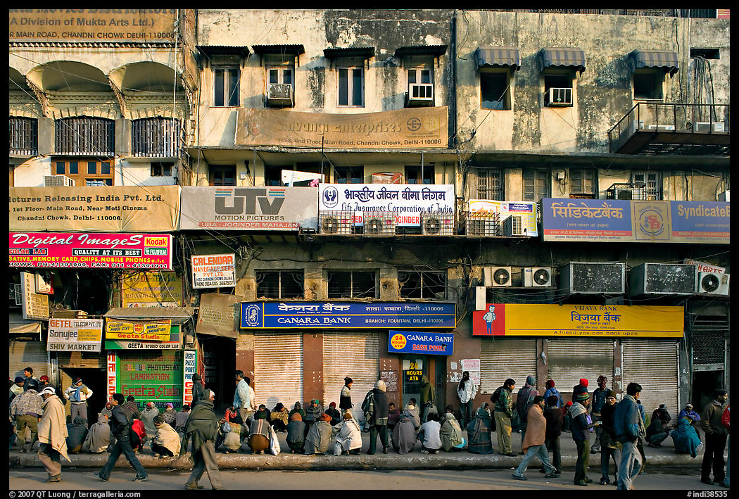 Street with many people waiting in front of closed stores, Old Delhi. New Delhi, India