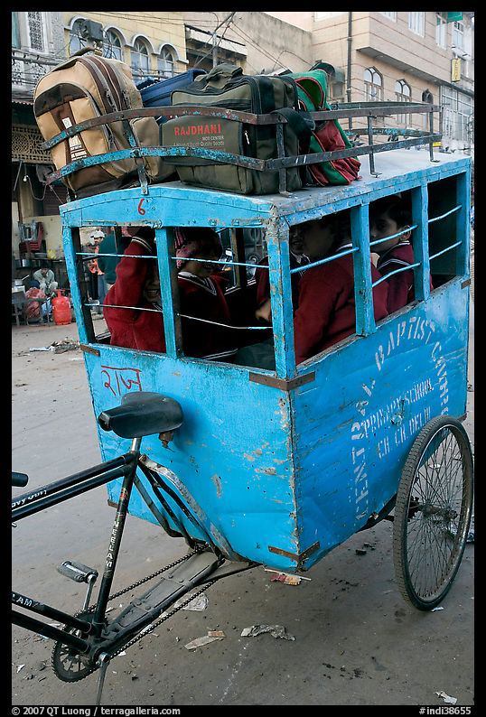 Schoolchildren in an enclosed  box towed by cycle. New Delhi, India