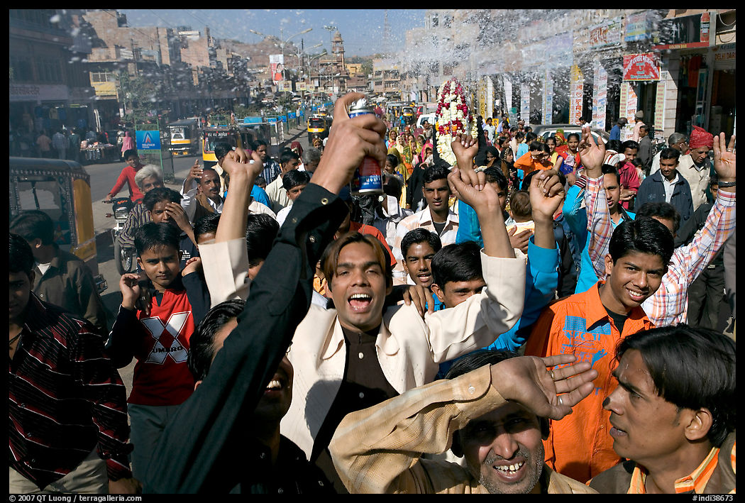 Young men celebrating and spraying wedding party in the street. Jodhpur, Rajasthan, India
