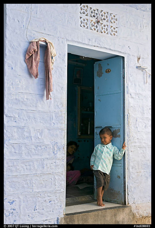 Young boy in doorway of house painted light blue. Jodhpur, Rajasthan, India