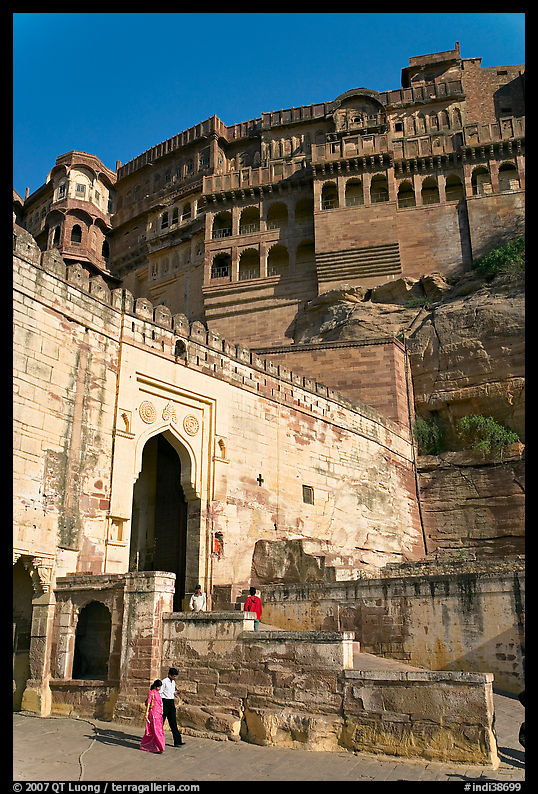 Couple walking below gate and high walls, Mehrangarh Fort. Jodhpur, Rajasthan, India