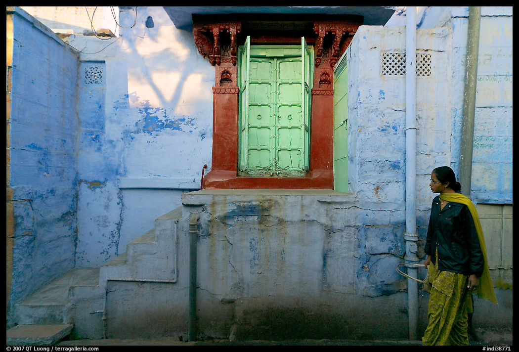 Woman walks infront of blue tinted whitewashed wall. Jodhpur, Rajasthan, India