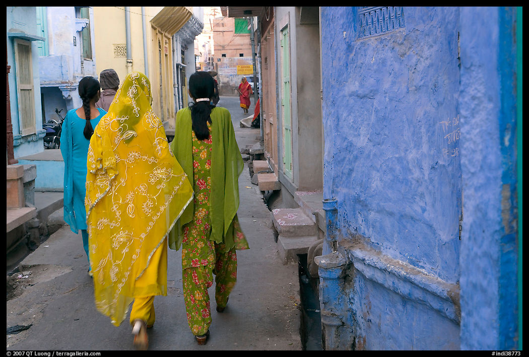 Women walking in narrow alley with blue walls. Jodhpur, Rajasthan, India