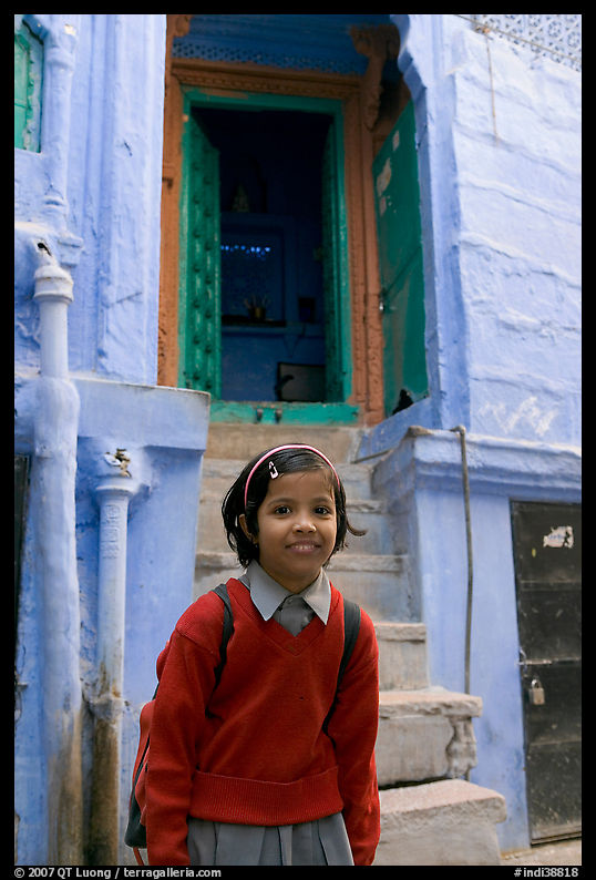 Schoolgirl standing in front of a house with blue tint. Jodhpur, Rajasthan, India