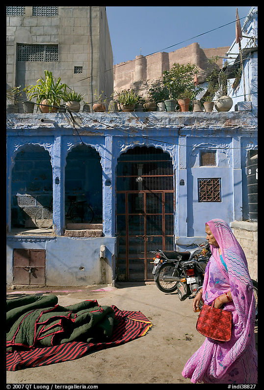 Woman in sari, blue house, and fort in the distance. Jodhpur, Rajasthan, India