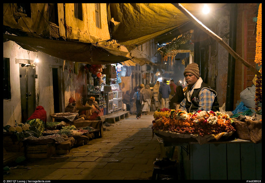 Flower vendor in  narrow old city alley at night. Varanasi, Uttar Pradesh, India