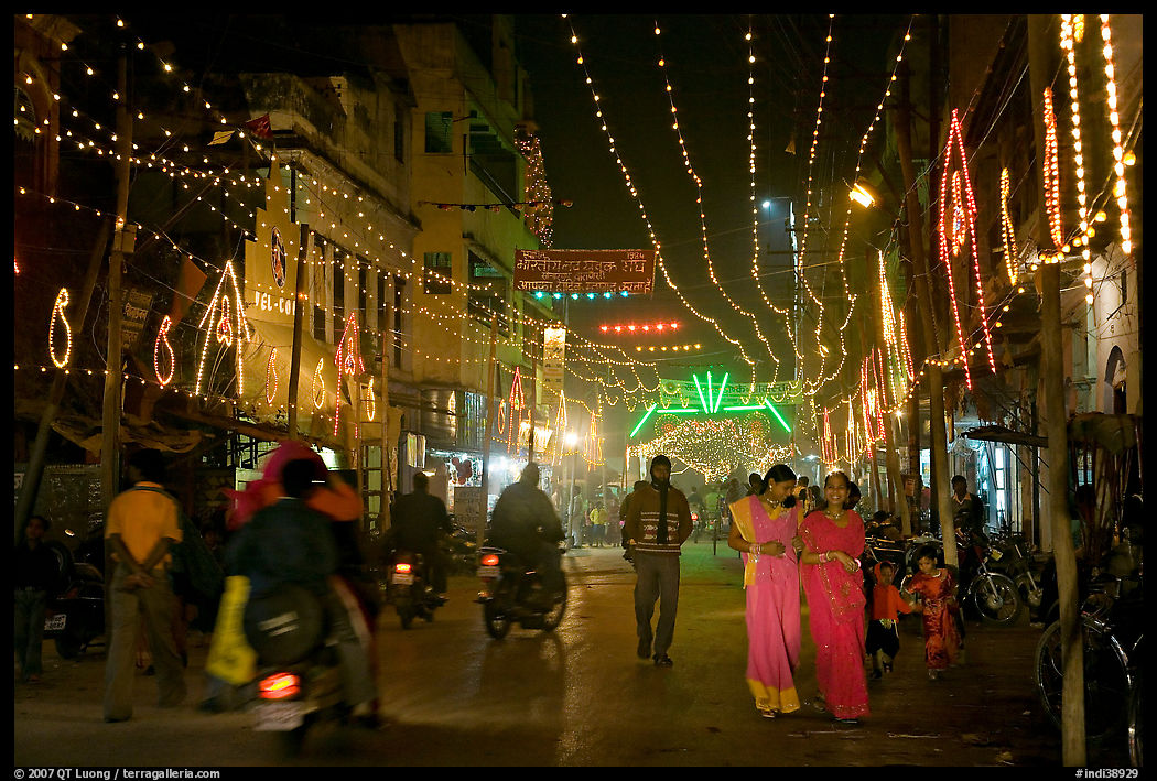 Women walking in street with illuminations. Varanasi, Uttar Pradesh, India