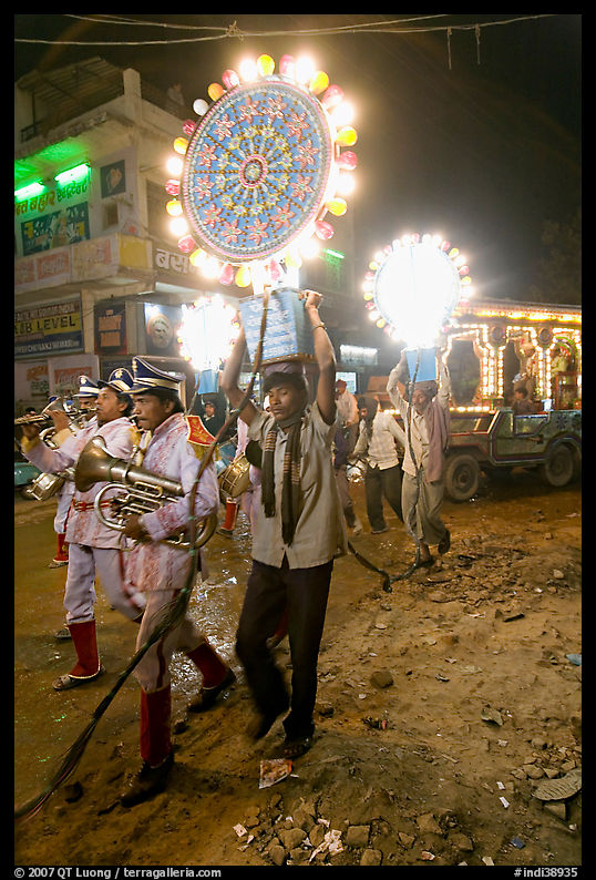 Uniformed musicians and men carrying lights during wedding procession. Varanasi, Uttar Pradesh, India