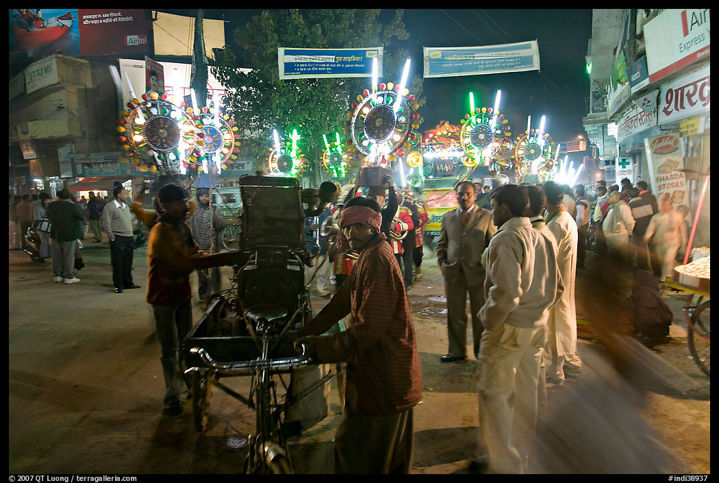 Men pulling generator on bicycle to power lights during wedding procession. Varanasi, Uttar Pradesh, India
