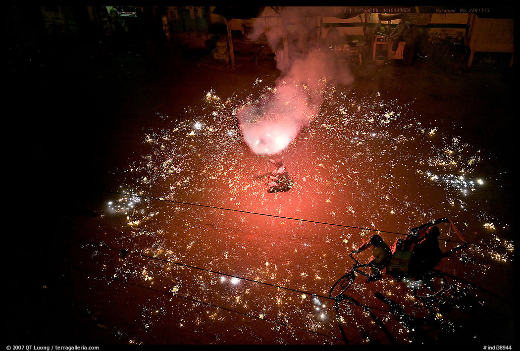 Man firing fireworks in middle of street ahead of wedding procession. Varanasi, Uttar Pradesh, India