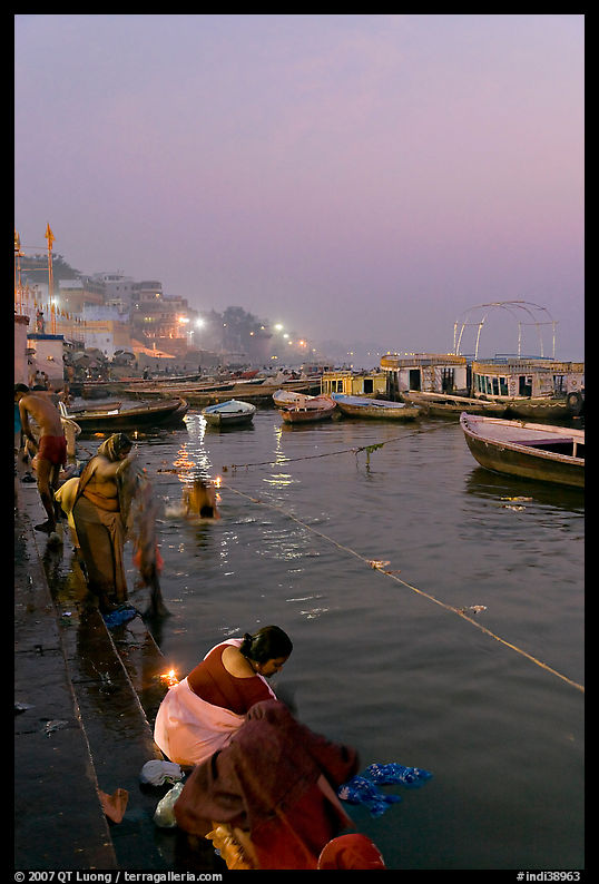 Women soaking clothes in the Ganges River at dawn. Varanasi, Uttar Pradesh, India