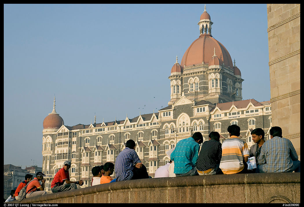 Men sitting in front of Taj Mahal Palace Hotel. Mumbai, Maharashtra, India